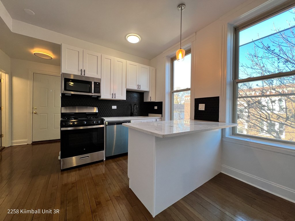 A kitchen with a white island and stainless steel appliances.