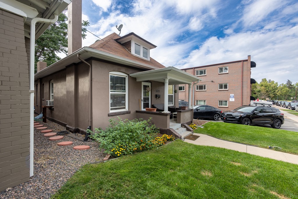 a small brown house with a lawn and a sidewalk