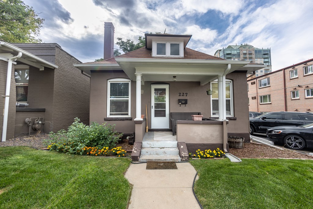 the front of a brown house with a sidewalk and grass
