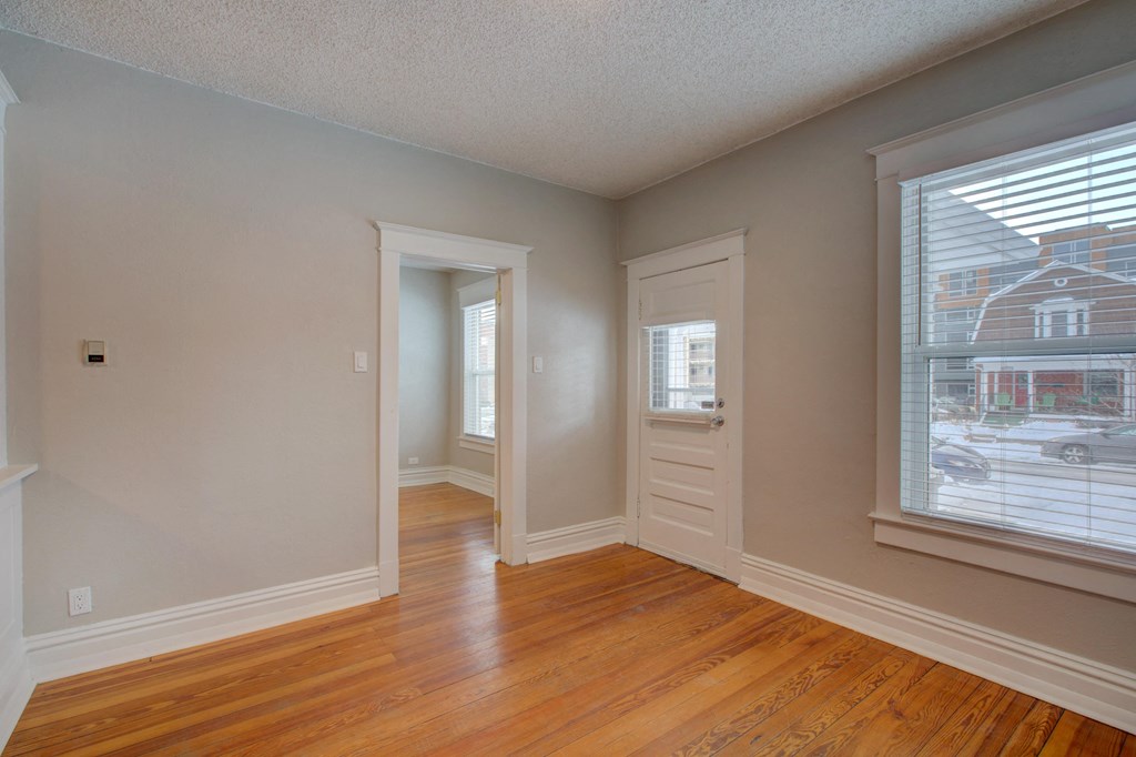 an empty living room with a large window and wooden floors