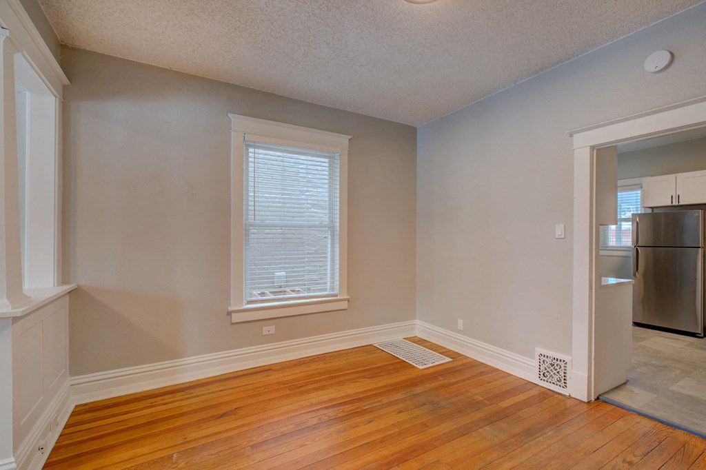 an empty living room with wood flooring and a window