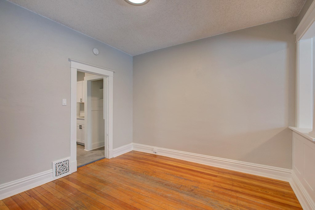 an empty living room with wood floors and a door to a closet