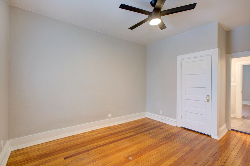 an empty room with wood floors and a ceiling fan
