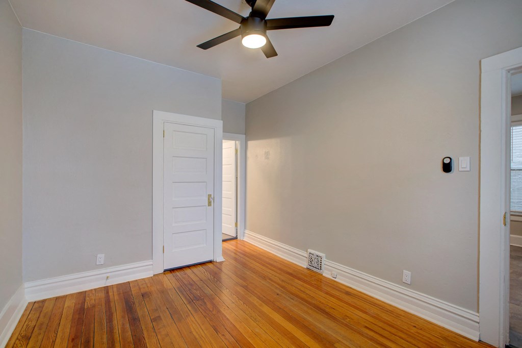 an empty living room with wood floors and a ceiling fan