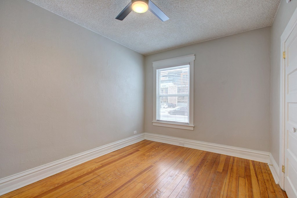 an empty living room with wood floors and a window