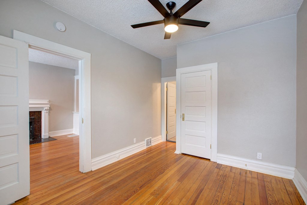 an empty living room with wood floors and a ceiling fan