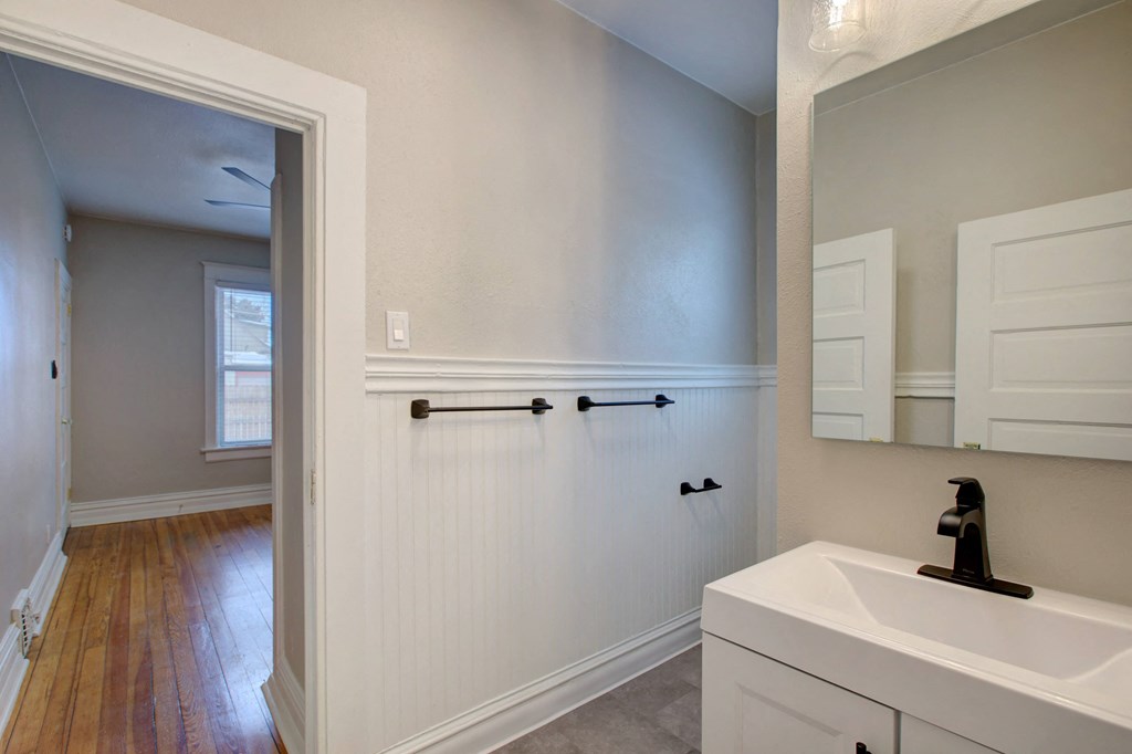 a bathroom with a sink and a mirror and a hallway with a door to a