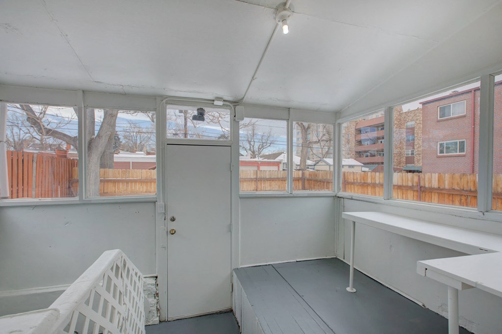 an enclosed porch with a door and many windows