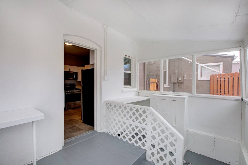 a small porch with a white railing and a window