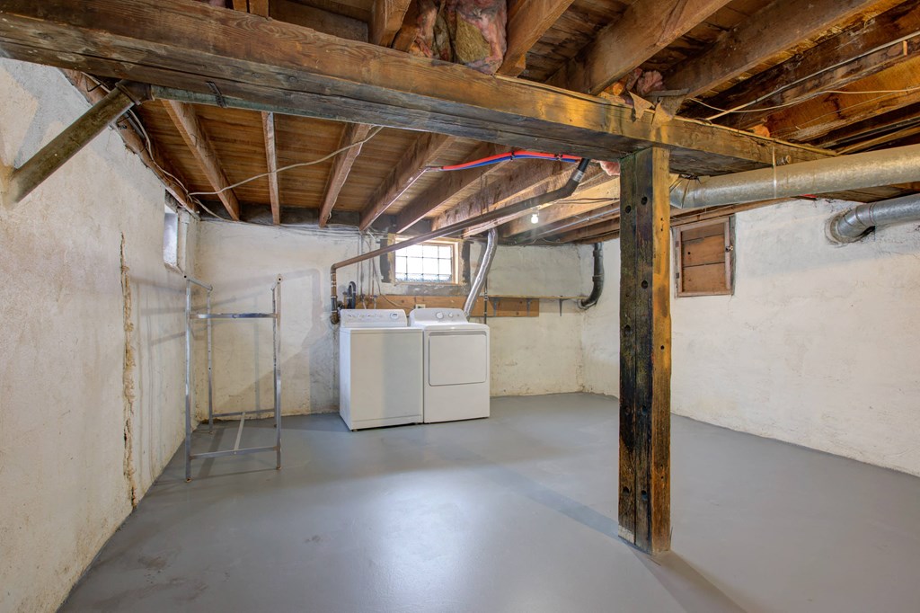 an unfinished basement with a refrigerator in the middle of it