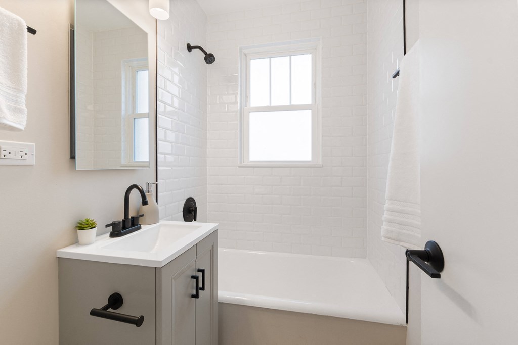 a white bathroom with a sink and a bath tub