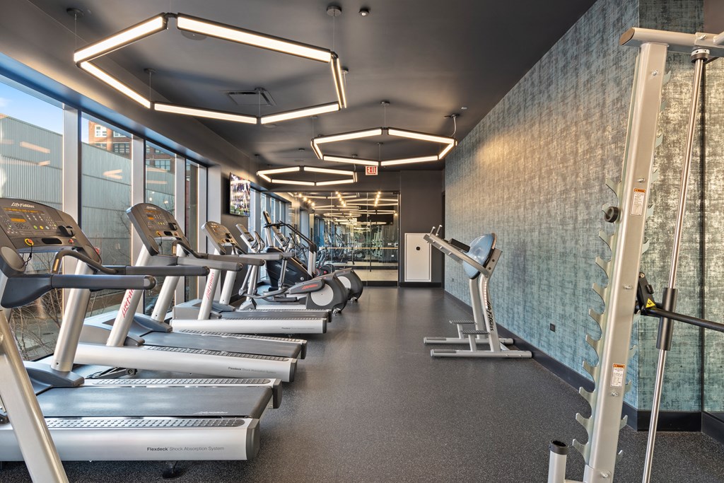a cardio room with cardio equipment and windows in the fitness center