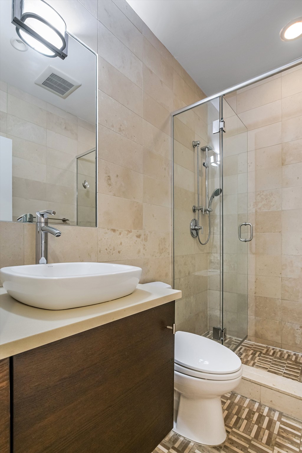 A bathroom with a white sink, toilet, and a glass shower stall.
