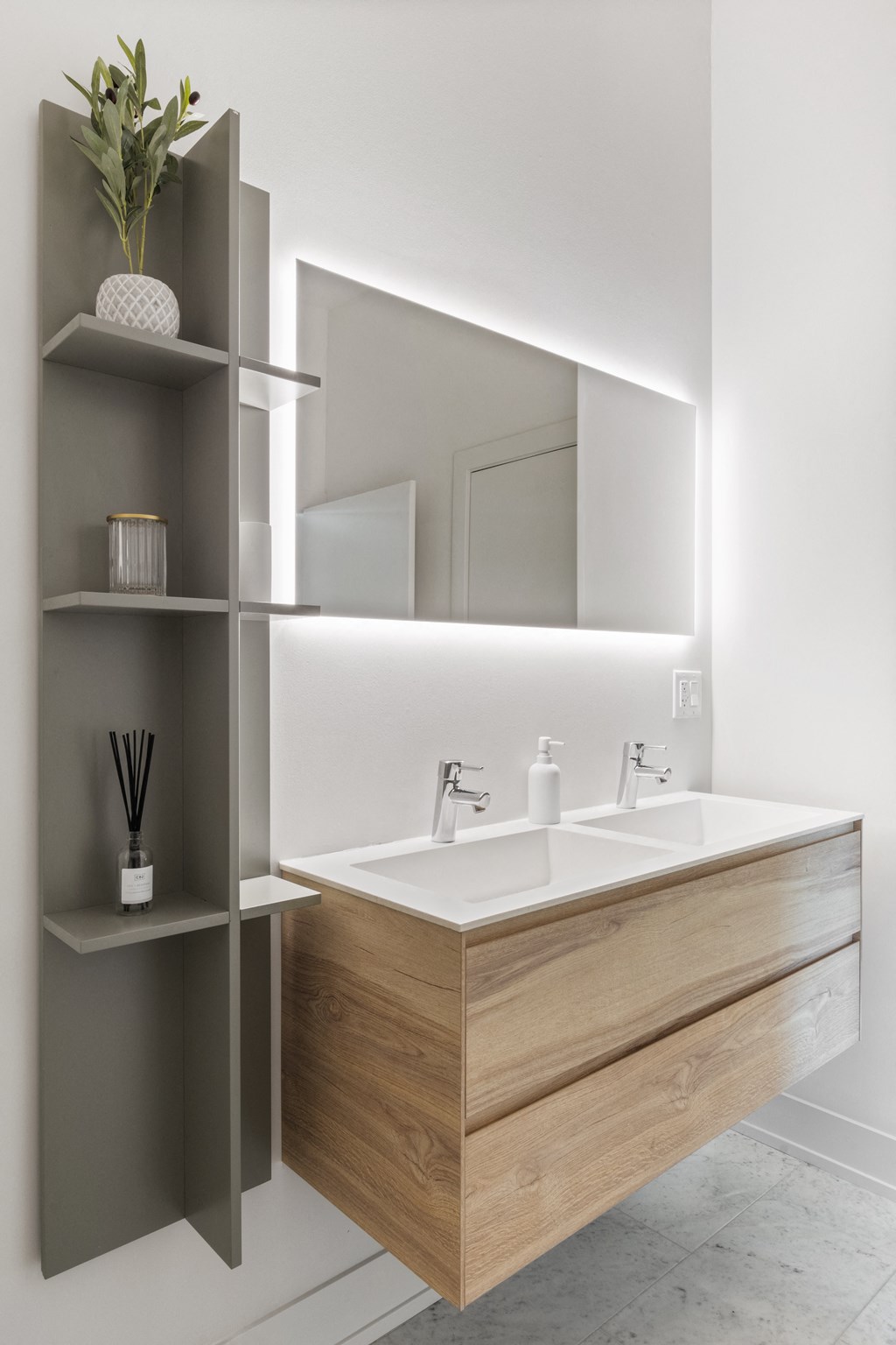 A bathroom with white walls and a wooden vanity with two sinks and a mirror