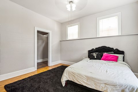 A bedroom with a bed, pillow, and a rug.