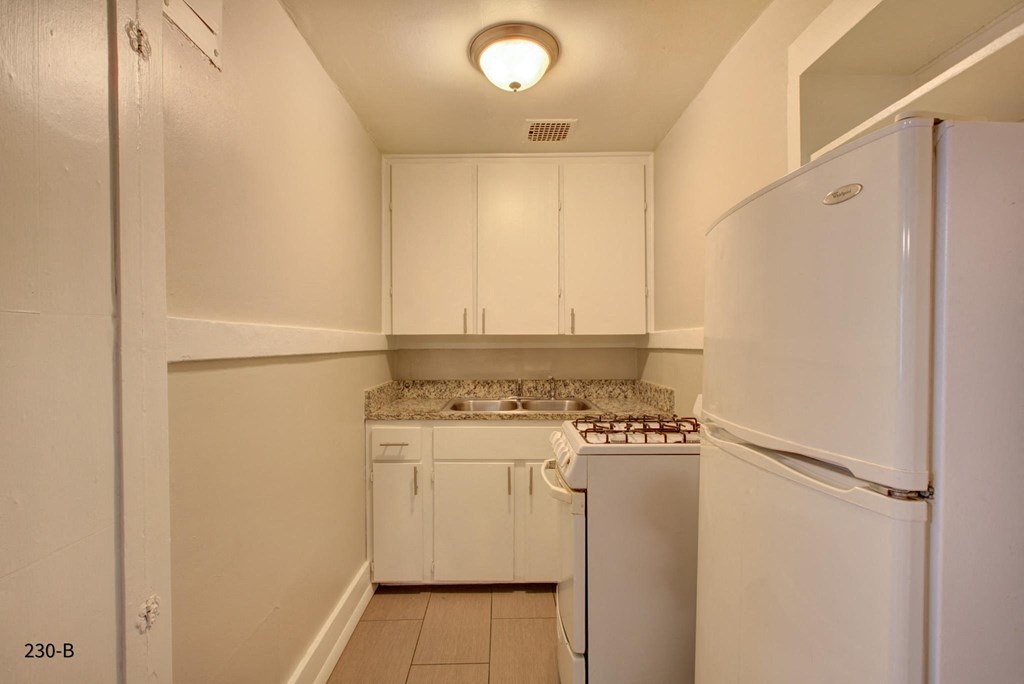 a kitchen with white cabinets and a refrigerator