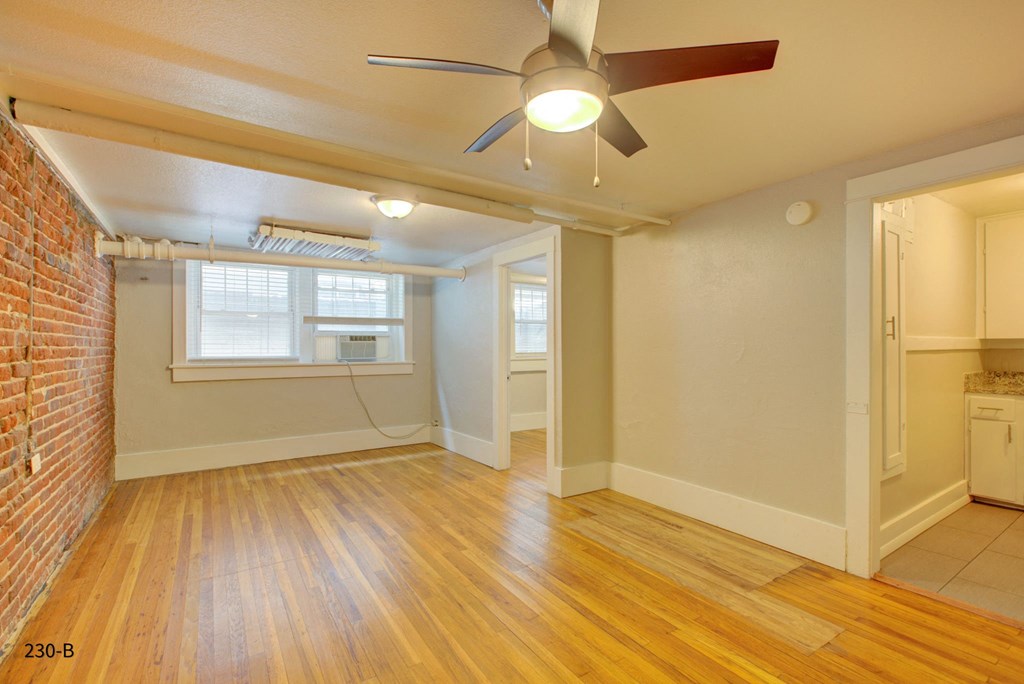 an empty living room with a ceiling fan and a window