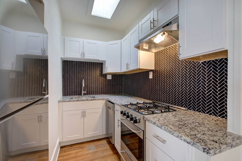A kitchen with white cabinets and a granite countertop.