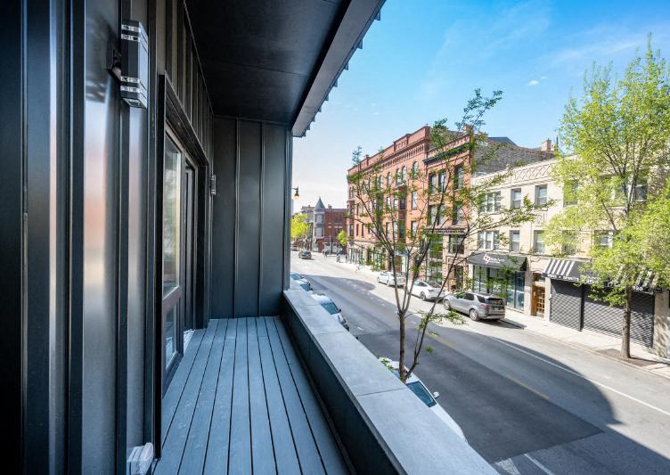 a large balcony with a wooden bench and a city street in the background