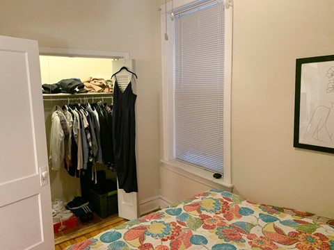 A bedroom with a bed, a wardrobe, and a painting on the wall.