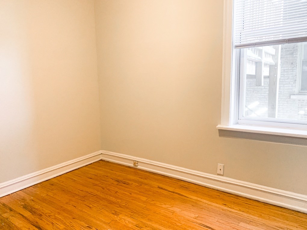 an empty room with wooden floors and two windows