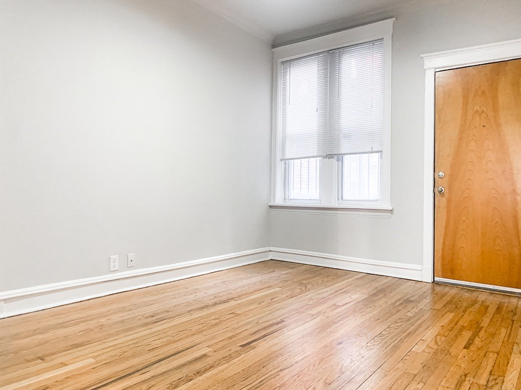 an empty room with wood floors and a door and a window