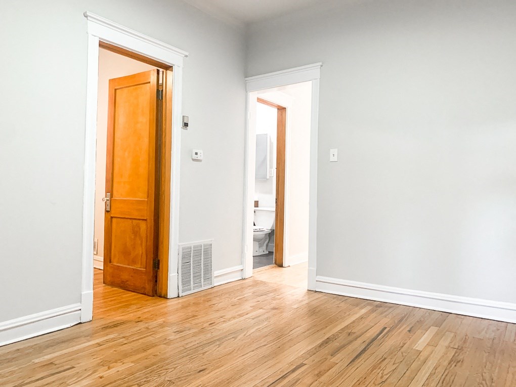 an empty room with a wooden floor and a door to a bathroom