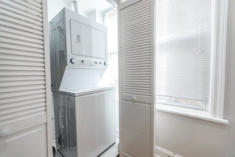 A white refrigerator is in a kitchen next to a window.