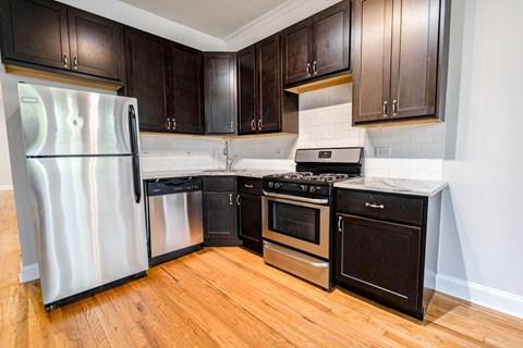 A kitchen with a refrigerator, oven, and stove.
