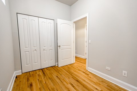 A room with three white doors and a wooden floor.