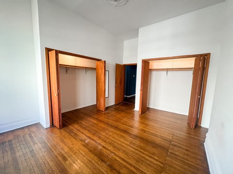 A room with wooden floors and white walls with three open doors.