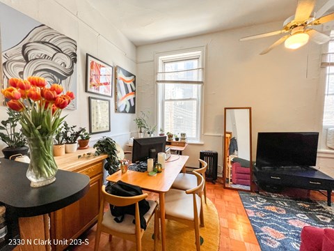 A living room with a television, a desk, and a chair.