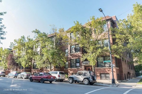 a brick apartment building on a city street with parked cars