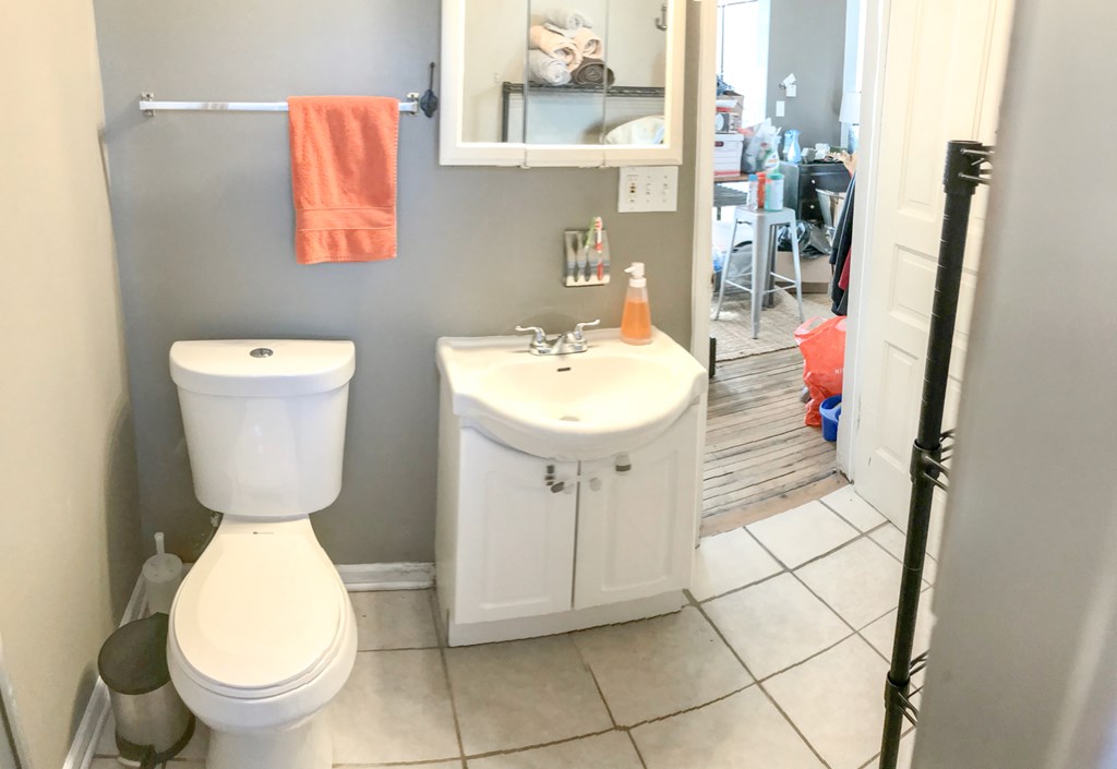 A bathroom with a toilet, sink, and a mirror.