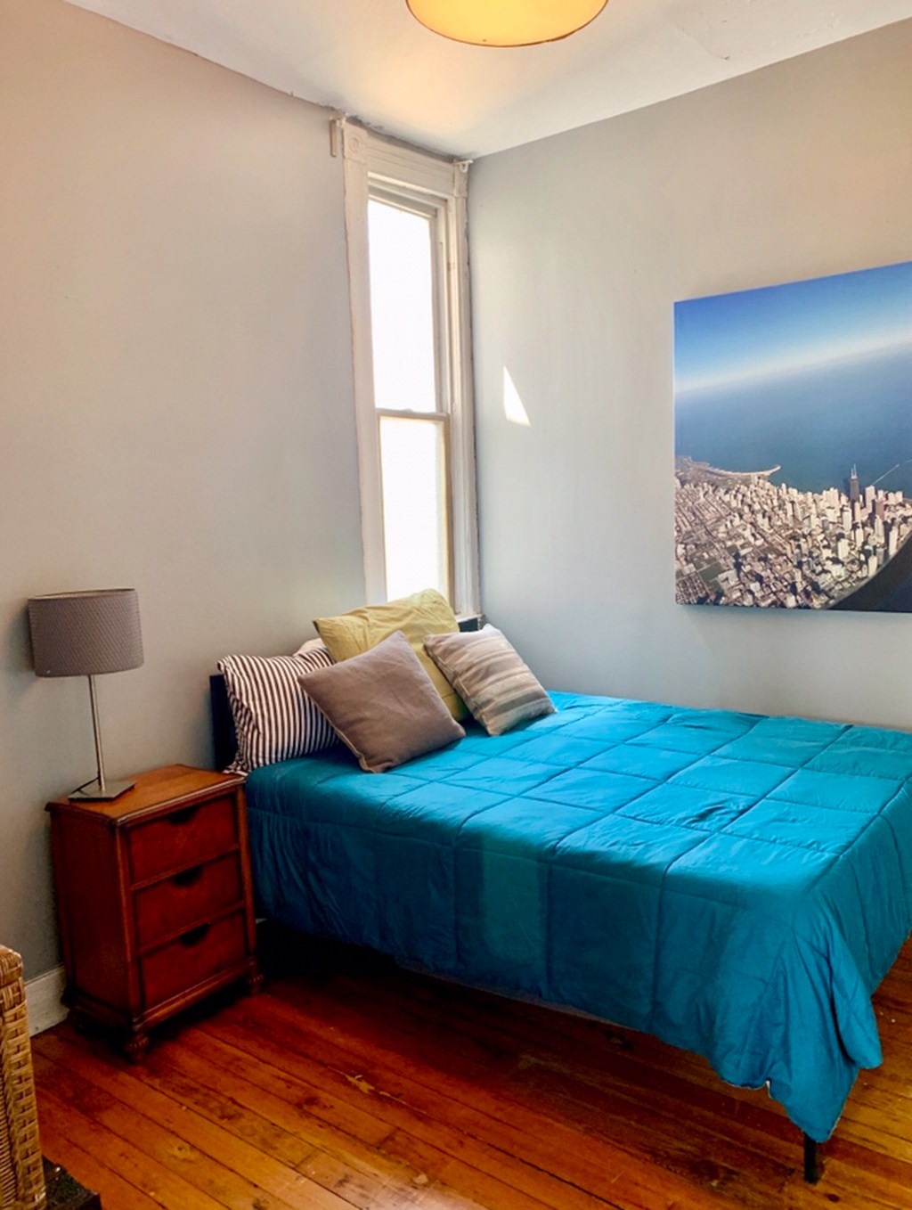 A bedroom with a blue bedspread and a wooden nightstand.