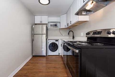 A kitchen with a black counter and a stainless steel refrigerator.