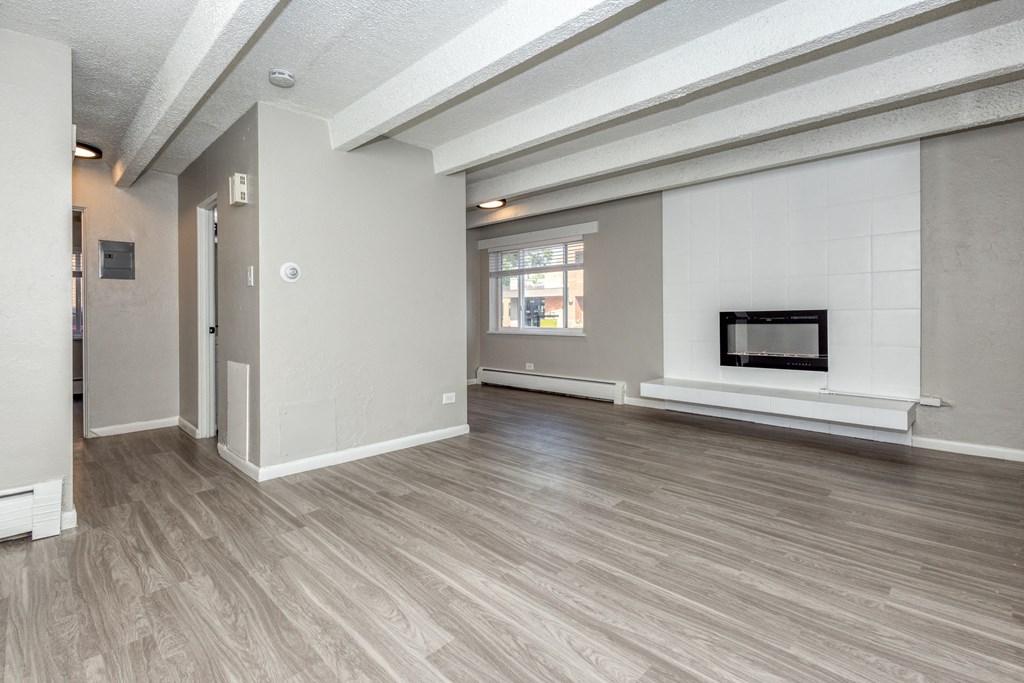the living room and dining room of an apartment with a fireplace