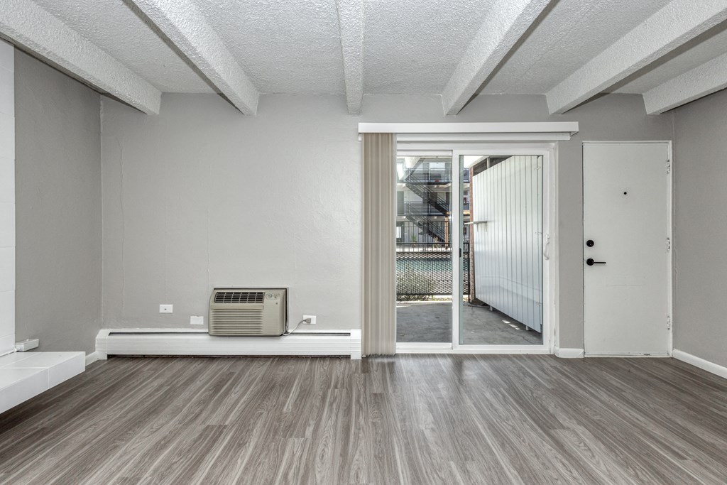 the living room of an empty apartment with a door to a patio