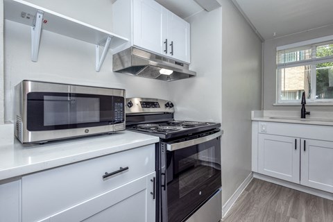 a kitchen with white cabinetry and black appliances and a window