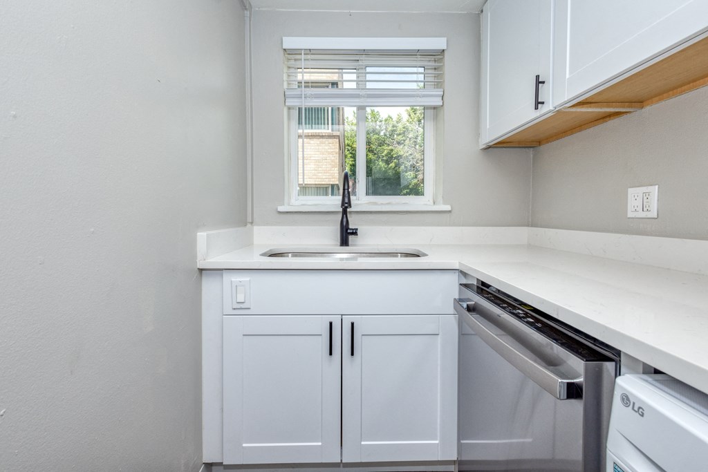 an empty kitchen with white cabinets and a window