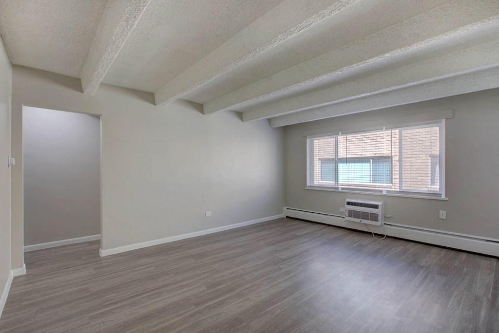 an empty living room with wood floors and a window
