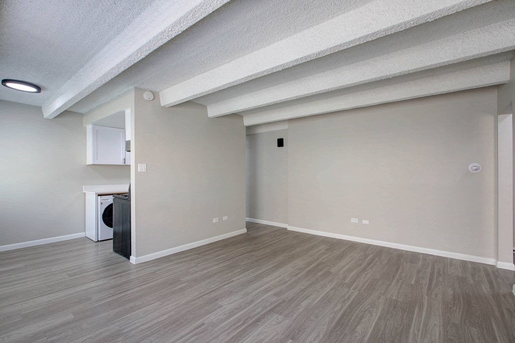 the spacious living room and kitchen in a new home with white walls and wood floors