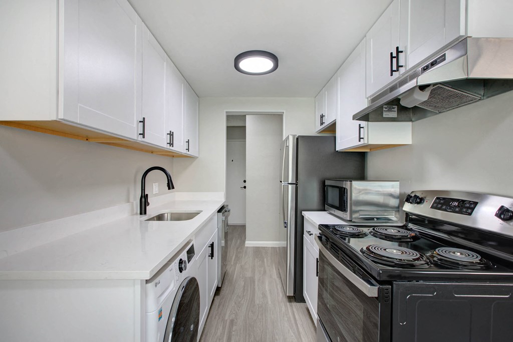 a kitchen with white cabinets and a stove and a refrigerator
