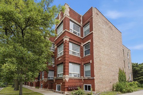 A red brick building with a tree in front.