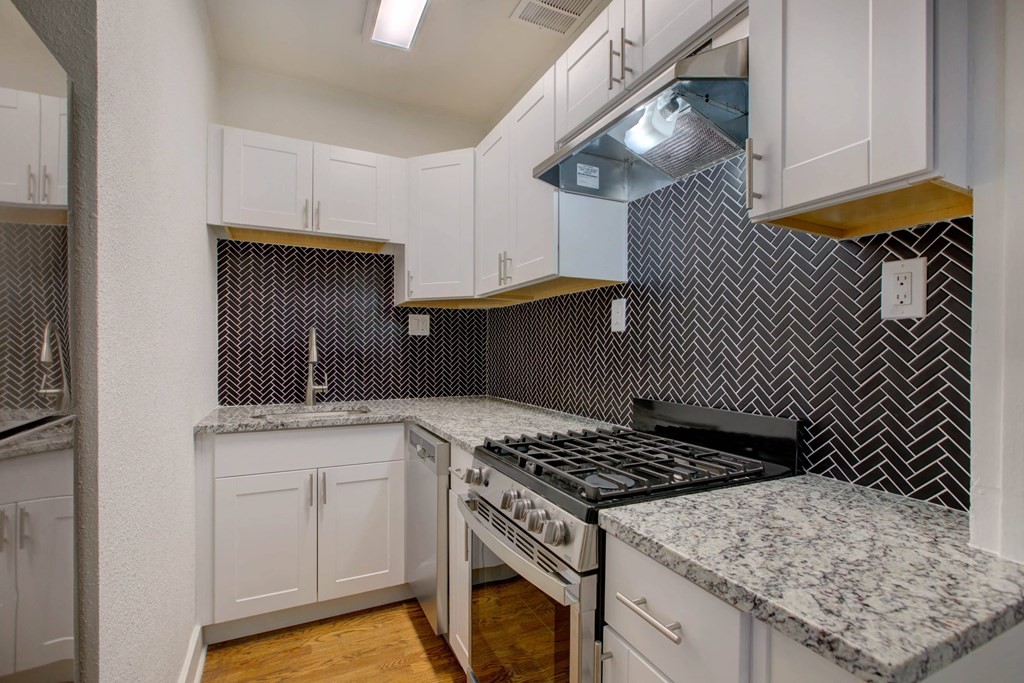 a kitchen with white cabinets and marble counter tops