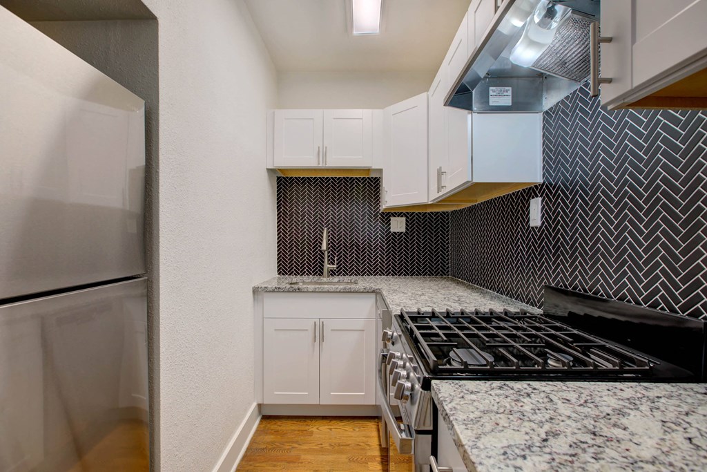 a kitchen with white cabinets and granite counter tops and a stove and refrigerator