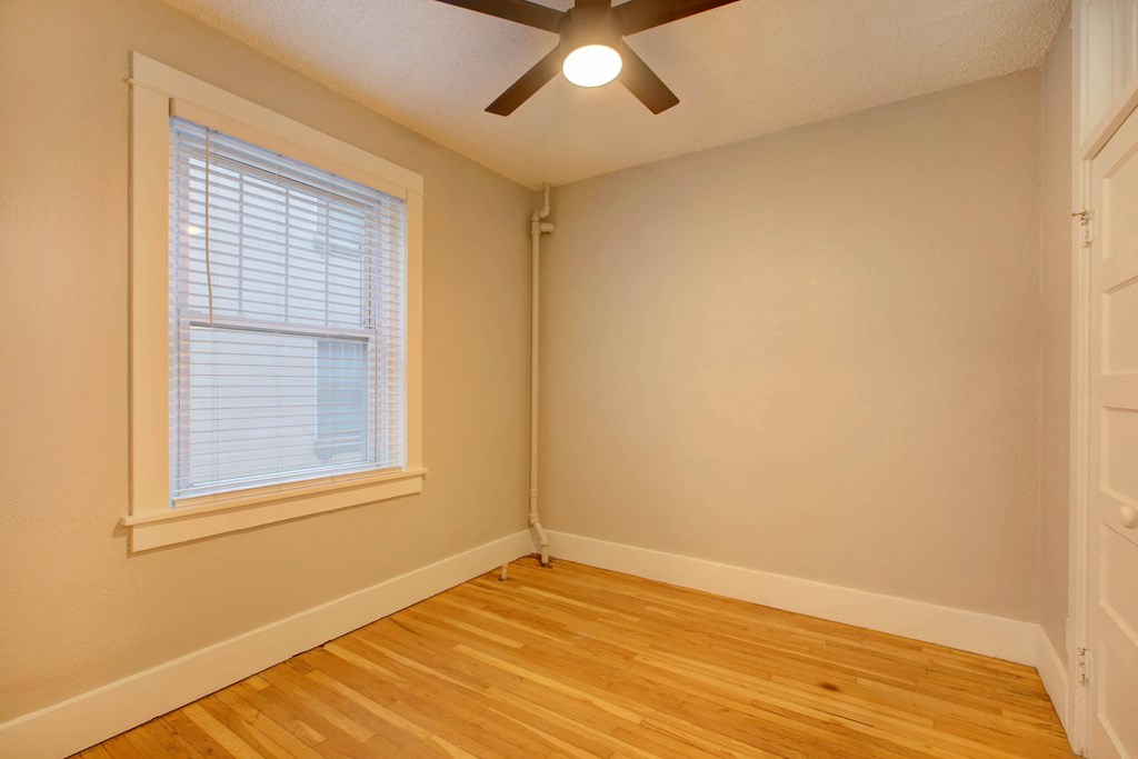 the bedroom of a house with a ceiling fan and a window