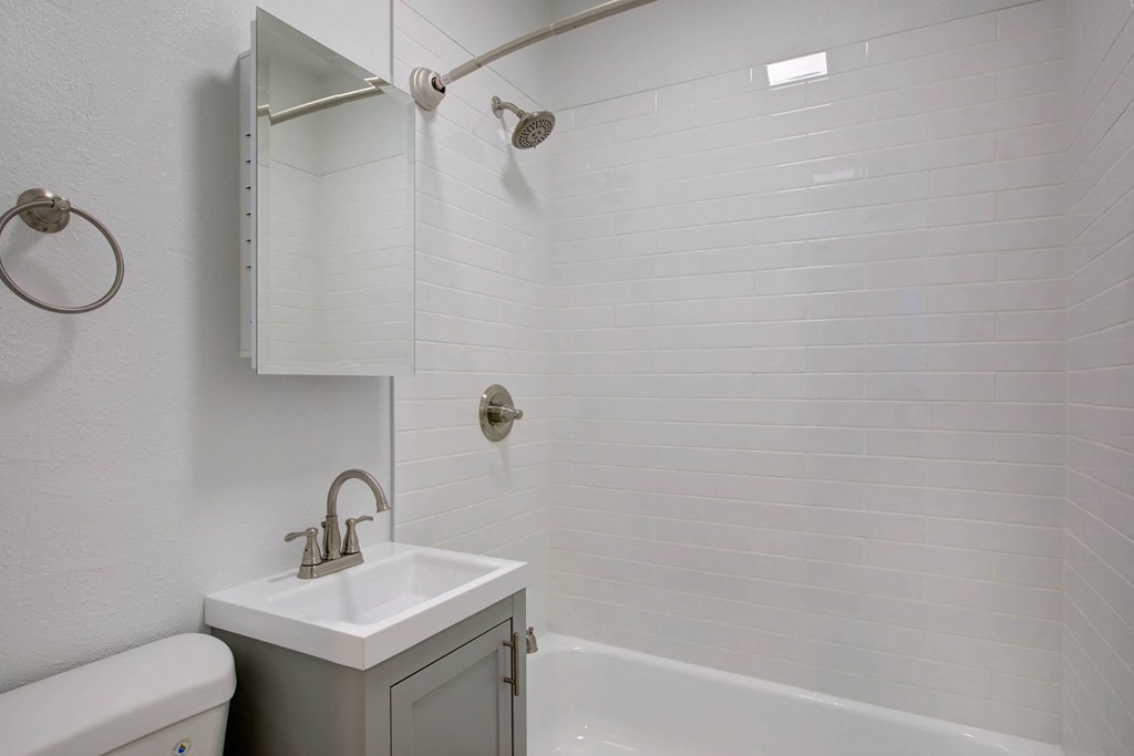 a white bathroom with a sink and shower and a toilet