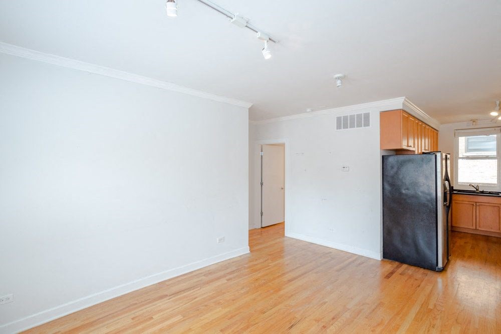 an empty living room and kitchen with a wood floor and white walls