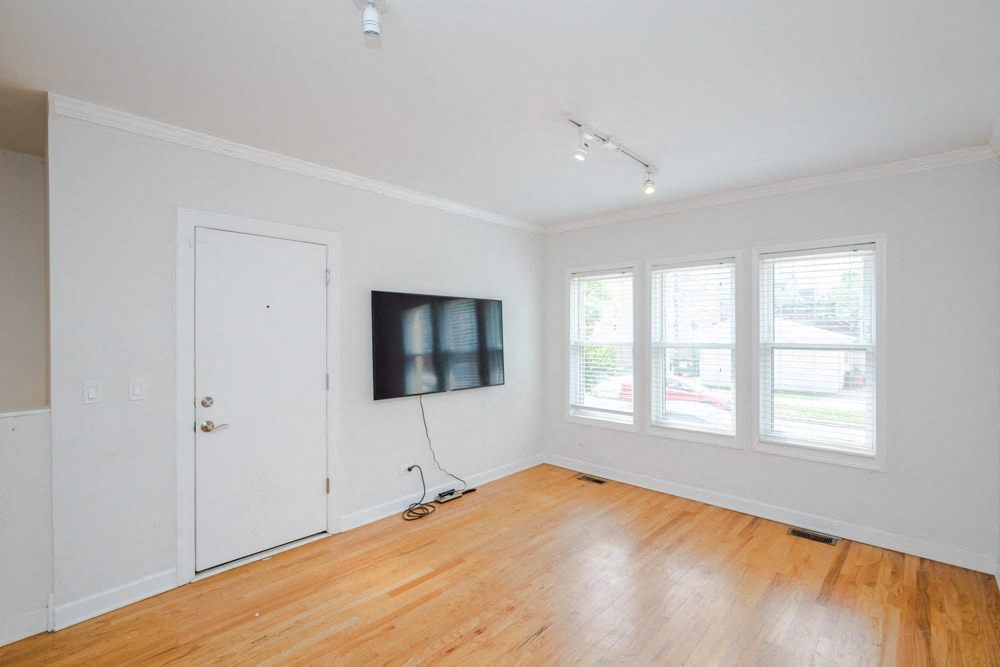an empty room with a tv on the wall and a wooden floor